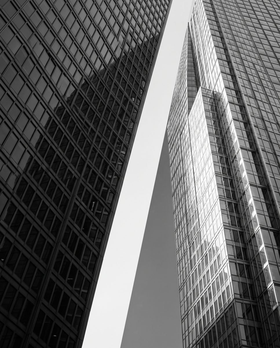 Two office towers photographed from below, a wedge of sky between them