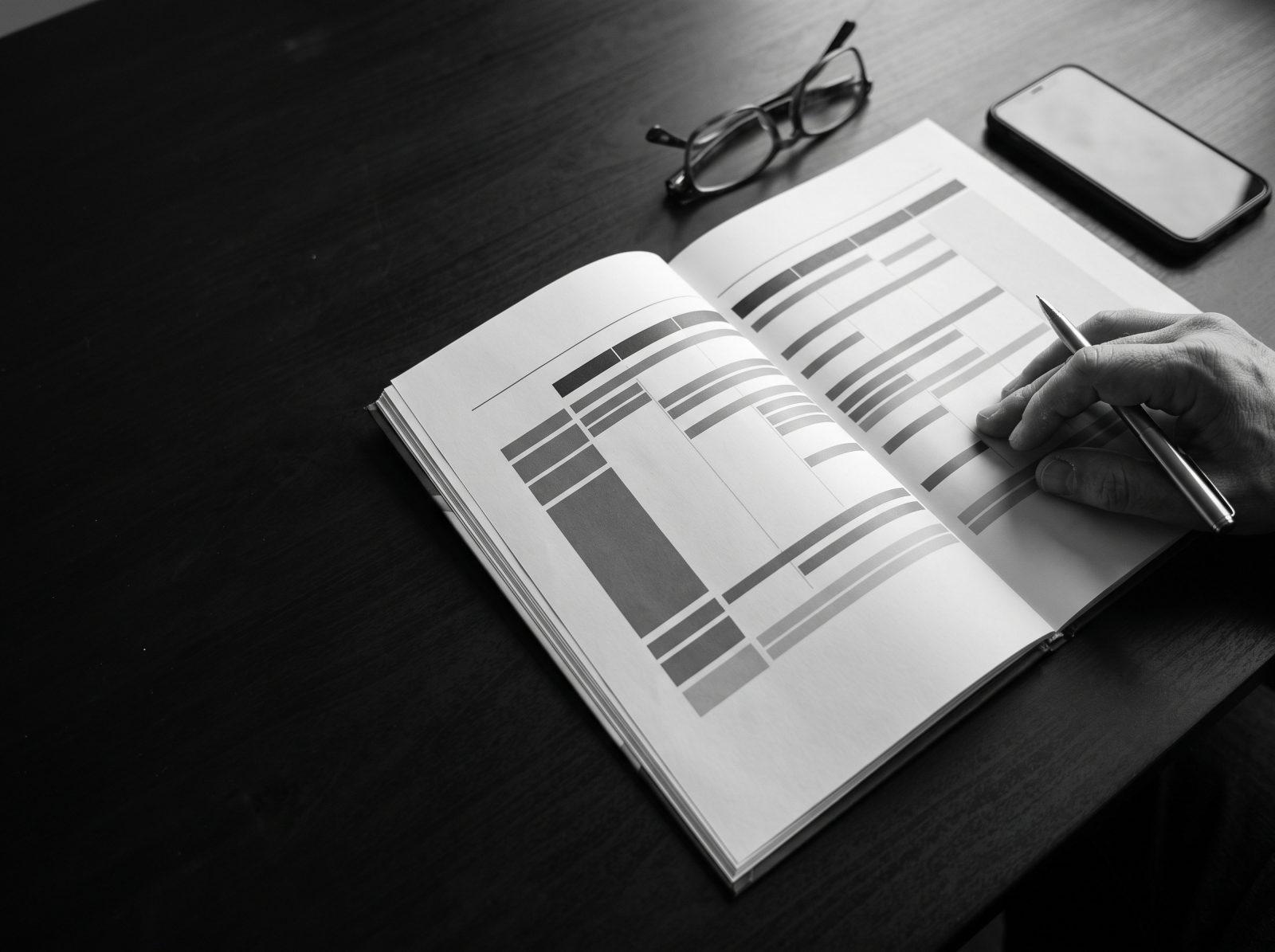 A consulting report lying open on a desk, a hand marking a plan with a pen